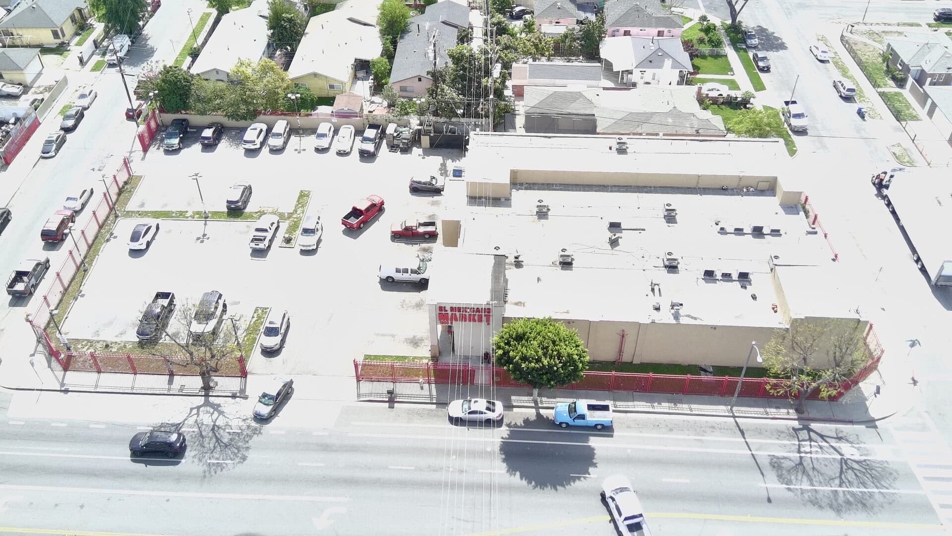Mid-altitude drone view — building, parking field, and trade-area context