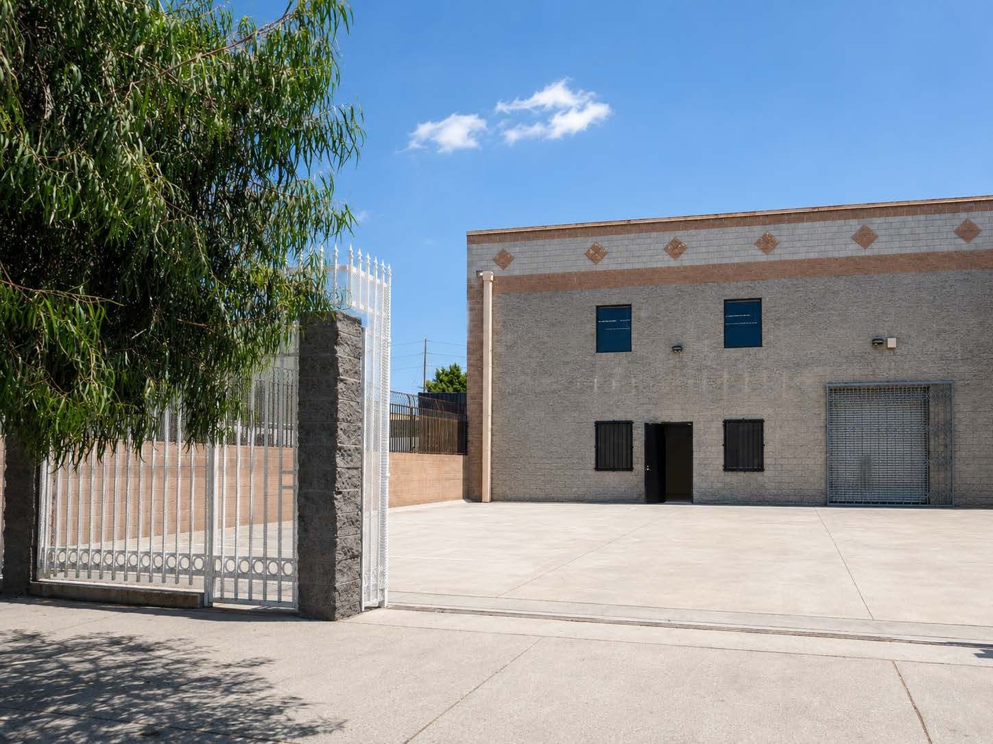 Gated entry at 2120 S Main St with steel security fencing opening to the concrete yard