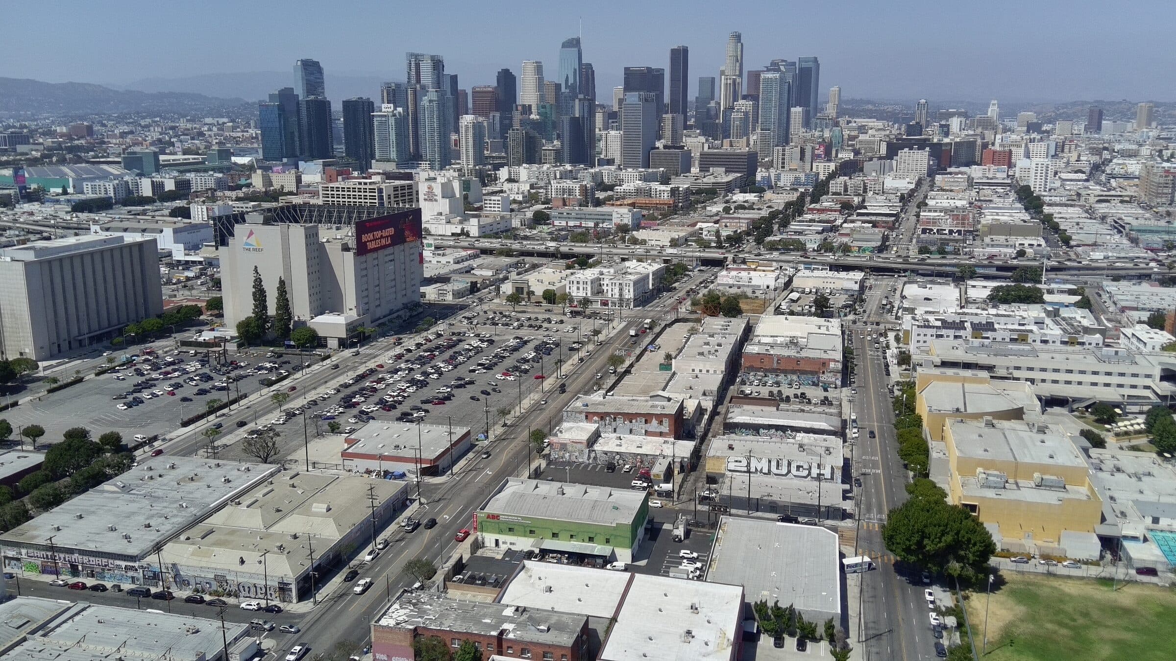 Drone aerial above 2120 S Main St looking up the South Main corridor to the Downtown Los Angeles skyline
