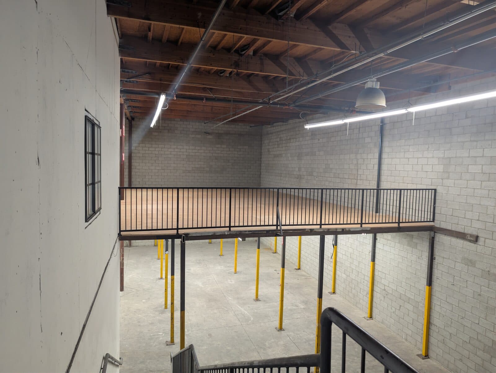Mezzanine overlook of the ground-floor warehouse volume at 2120 S Main St
